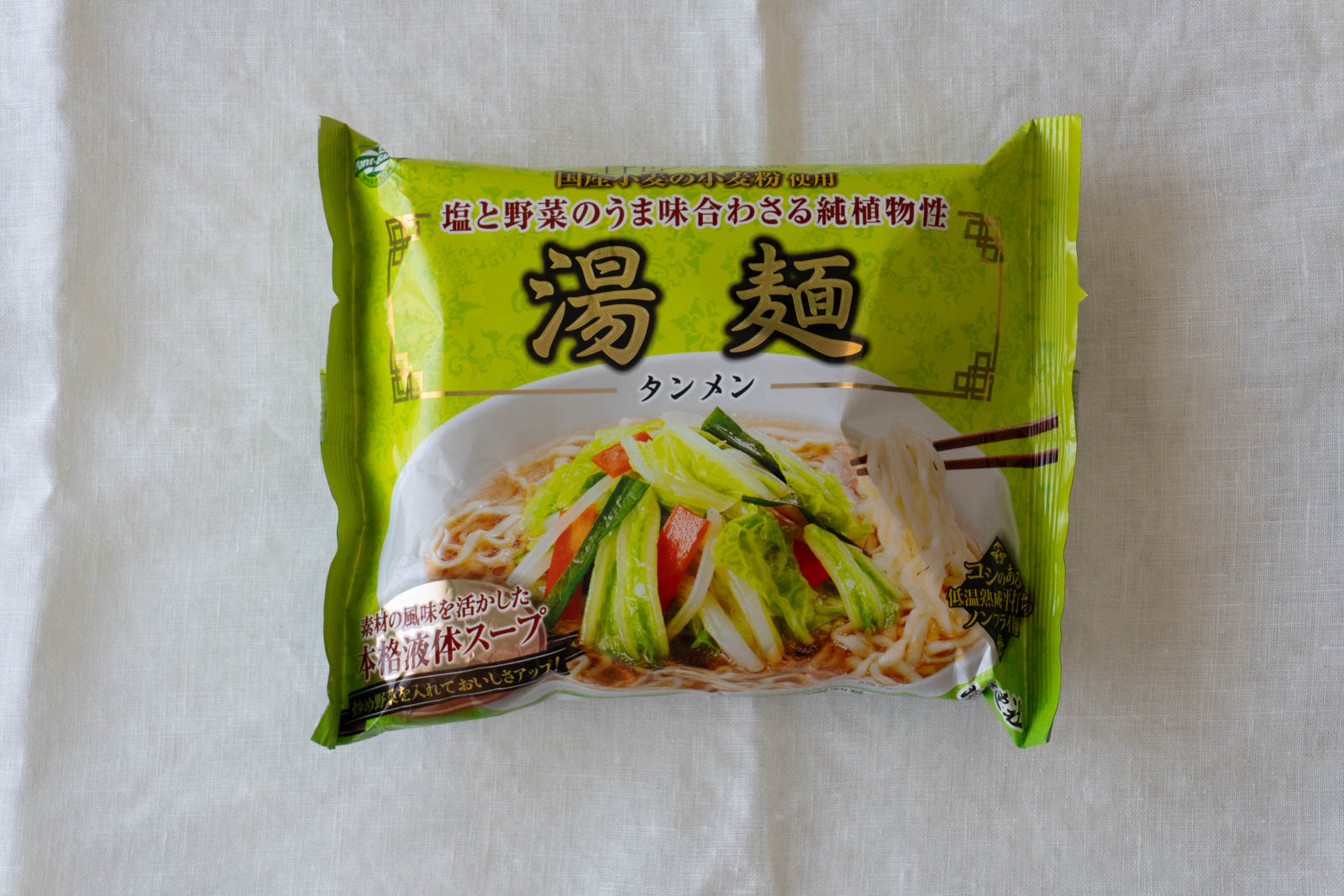 パッケージ表面。「国産小麦の小麦粉使用」「塩と野菜のうま味合わさる純植物性」などの表記。パプリカ、ピーマン、もやし、葉野菜を炒めてトッピングされた調理例の写真。