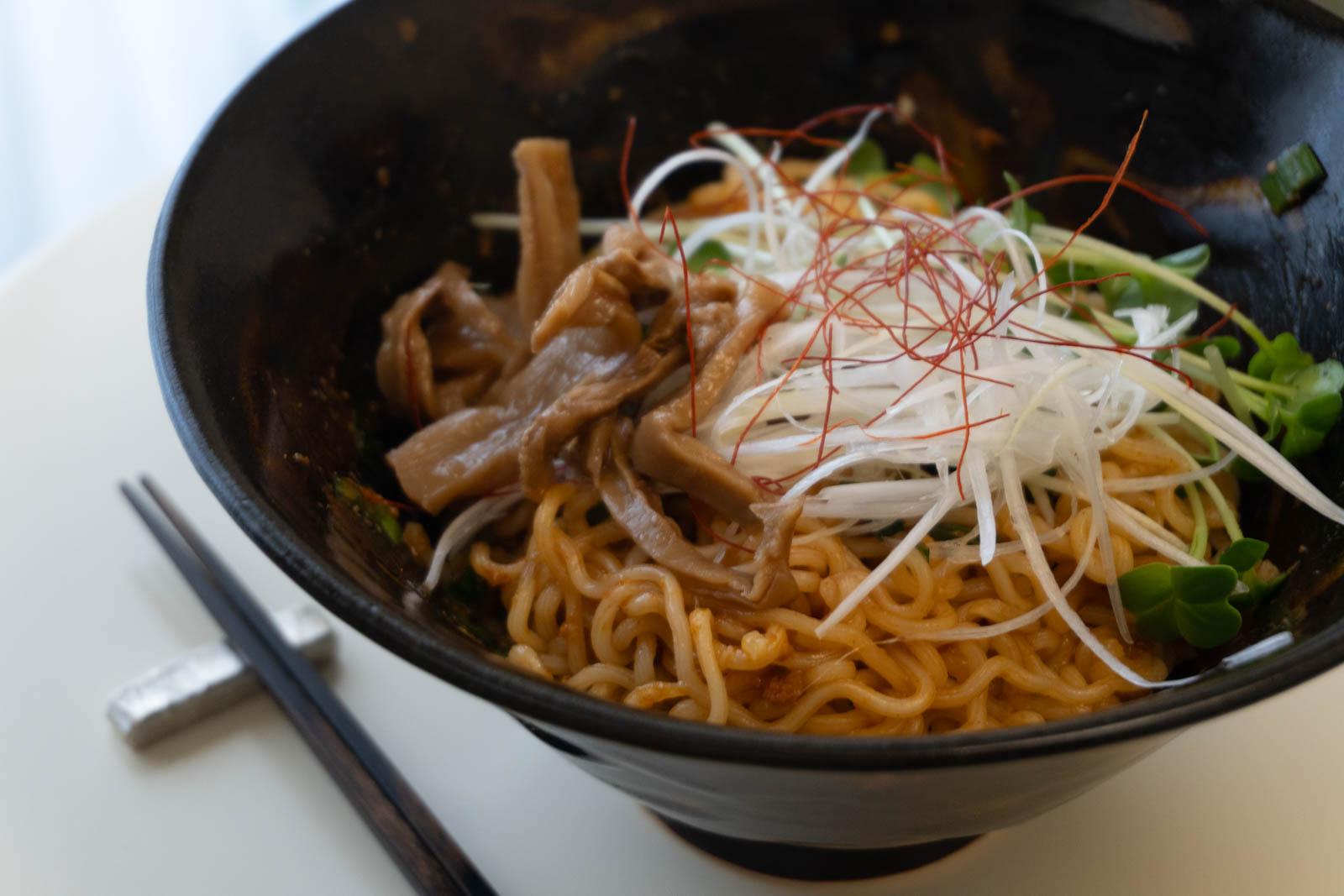 調理して器に盛ったラーメン。ニラが混ぜられ、メンマ、かいわれ、白髪ネギ、糸唐辛子がトッピングされている。