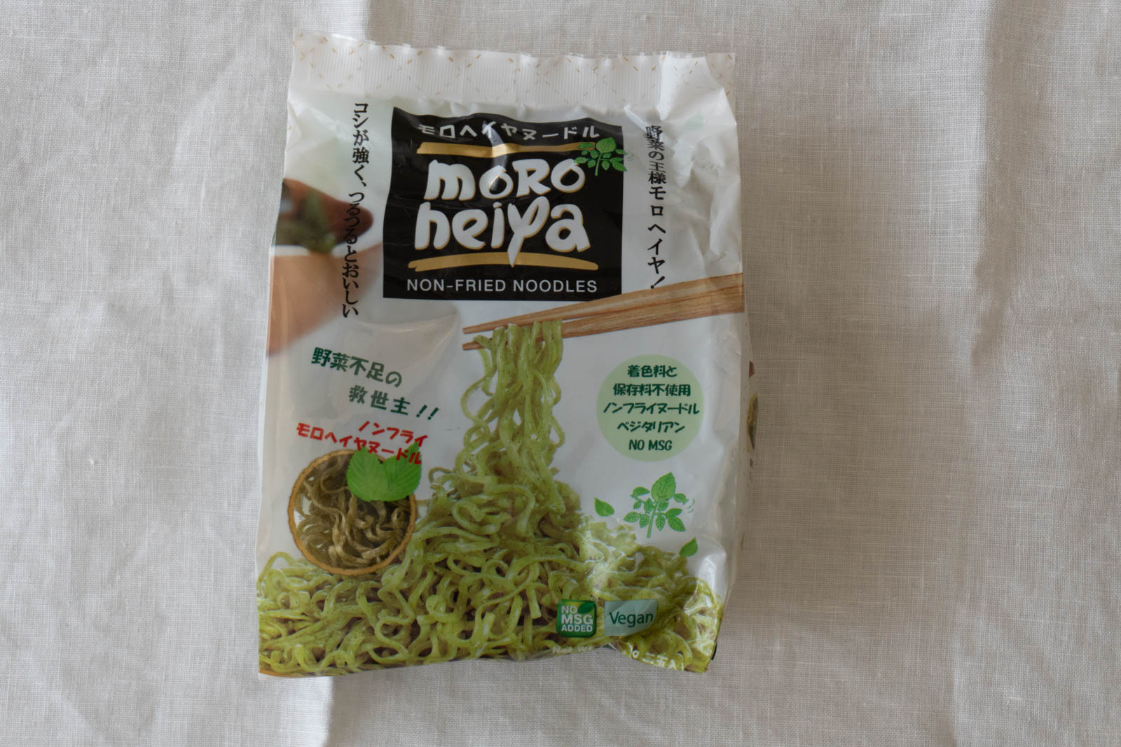 パッケージ表面。「着色料と保存料不使用」「ノンフライヌードル」「ベジタリアン」「NO MSG」「Vegan」「野菜不足の救世主！！」などの表記。緑色で平たいちぢれ麺の写真。